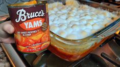 a person holding a can of bruce's yams on top of a stove