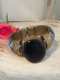 "Lovely vintage Cloisonné hinged brass bracket. Pink and blue floral designs. Large black celluloid stone embellishment. Decorative hinged closure. Very pretty. This bracelet was given to me by my sister who wore it in the 70s then stored it for years. It is in great vintage condition. Diameter is 2.5\", width is 0.5\". Remember: Vintage is never perfect. Each vintage item was owned and used for years before it was found and listed in this shop. Please see all photos as they are part of the desc Vintage Adjustable Hinged Bracelet, Vintage Black Enamel Bracelet Jewelry, Vintage Adjustable Hinged Cuff Bracelet, Vintage Adjustable Hinged Bracelets, Vintage Black Enamel Bracelet, Vintage Black Metal Cuff Bracelet, Vintage Adjustable Hinged Bangle, Vintage Metal Hinged Cuff Bracelet, Vintage Metal Cuff Bracelet With Hinge