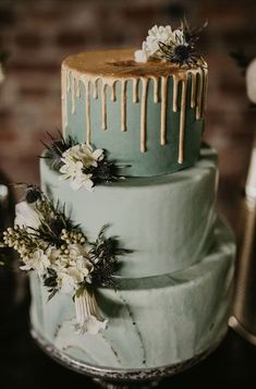 a three tiered cake with flowers and dripping icing