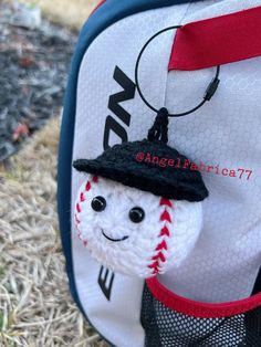 a baseball ornament hanging from the side of a backpack with a hat on it