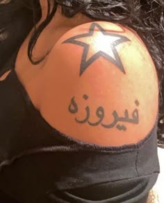 the back of a woman's shoulder with an arabic star on her upper arm