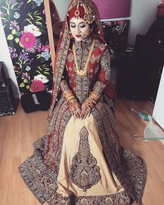 a woman in a red and gold wedding dress sitting on the floor next to a mirror