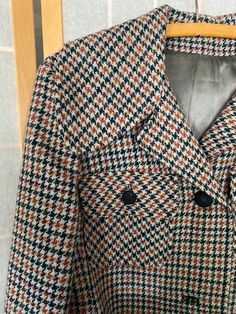 "1970's Juli de aroma houndstooth coat with a blue belt. Belt is made of a faux leather material that, being 50 years old, is now a little sticky to the touch and flakes off in the hand. Missing buttons 2 and 4 and the left pocket buttons. Bust: 40\" Shoulder to hem: 41\"" Brown Houndstooth Blazer For Fall, Brown Houndstooth Outerwear For Fall, Brown Houndstooth Blazer For Spring, Orange Wool Outerwear For Fall, Orange Outerwear For Office In Fall, Retro Houndstooth Blazer For Winter, Retro Houndstooth Winter Blazer, Retro Winter Houndstooth Blazer, Retro Belted Fall Outerwear