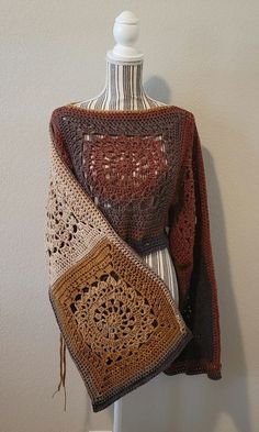 a crocheted shawl is displayed on a mannequin