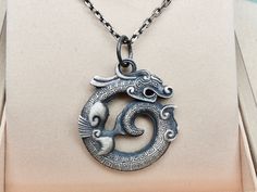 "Sterling silver oxidized Dragon pendant necklace with unique DOUBLE SIDE design , made with solid 925 sterling silver , with one complementary chain 18\" . Pendant size : 30 x 26mm Weight : 9.5 grams Thickness : 3.5mm For other Sterling Silver Necklaces , click here : https://www.etsy.com/shop/TibiCollection?section_id=24775360 Return to my shop's home page, click here : https://www.etsy.com/shop/tibicollection" Unique Oxidized Finish Necklaces, Silver Mens Necklace, Silver Necklace Mens, Sterling Silver Jewelry With Dragon Design Round Pendant, Unique Sterling Silver Necklace With Dragon Design, Mens Pendant Necklace, Sterling Silver Spiritual Necklace With Dragon Design, Silver Dragon Design Sterling Silver Necklace, Viking Oxidized Pendant Necklace