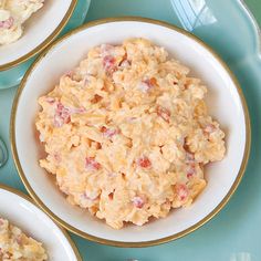 three bowls filled with macaroni and cheese on top of a blue tablecloth