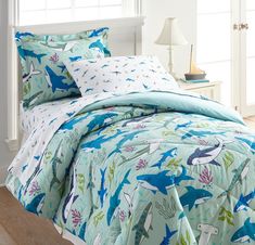 a bed covered in blue and green dinosaur comforters