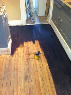 a wooden floor is being remodeled in a kitchen with paint on the floor and a brush