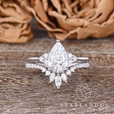 a pear shaped diamond engagement ring on top of a wooden table