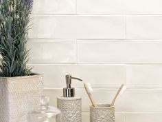 two toothbrushes and a soap dispenser in front of a white brick wall