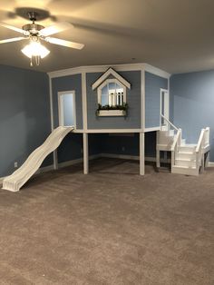 a play house with slide and stairs in the middle of an empty living room that is painted blue