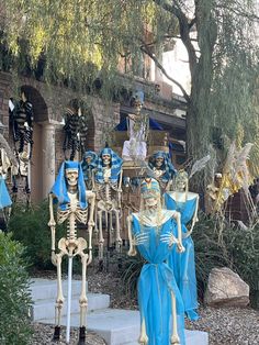 skeleton statues are displayed in front of a building with trees and bushes around them,