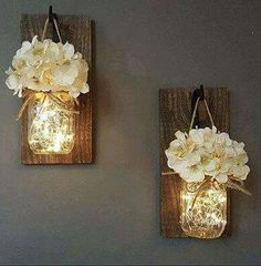 two mason jar wall sconces with flowers on them are hanging from the wall