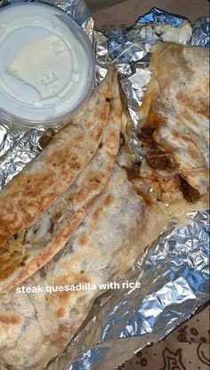 two quesadillas wrapped in aluminum foil with a cup of yogurt