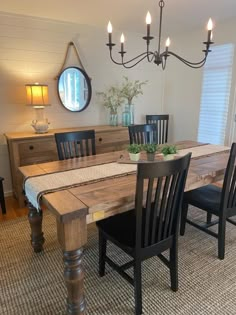 a dining room table with four chairs and a mirror on the wall