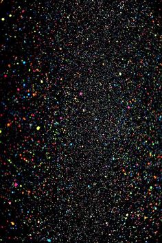 an abstract black background with multicolored confetti sprinkles on it