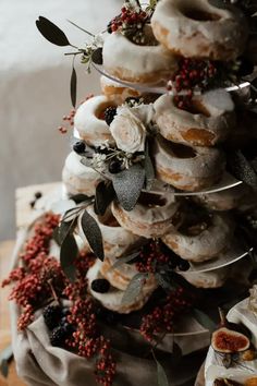 there are many donuts stacked on top of each other with berries and leaves around them