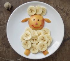 a white plate topped with sliced bananas and an orange in the shape of a sheep