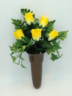 a vase filled with yellow roses and greenery