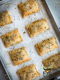 nine pastries on a baking sheet ready to go into the oven with sesame seeds