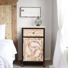 a bed room with a neatly made bed and a wooden cabinet on the sideboard