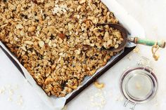 a pan filled with granola sitting on top of a table next to a spoon