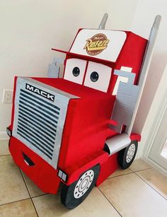 a red truck costume sitting on top of a tile floor next to a white wall