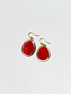 a pair of red earrings with green leaves on them