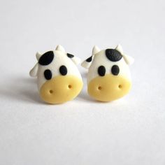 two small black and white cows are sitting next to each other on a white surface