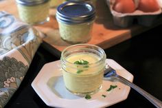 a small glass jar filled with food sitting on top of a white plate next to an egg