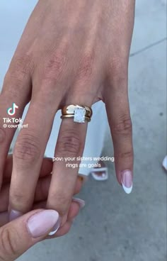 a woman's hand with two wedding rings on it