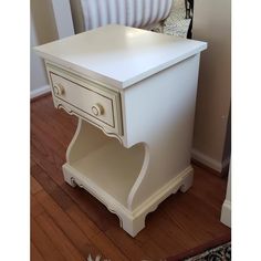 a white table with two drawers on the bottom and one drawer at the top, sitting in front of a radiator