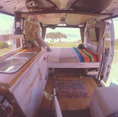 the interior of an rv with a bed and sink in it's rear end