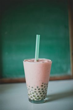 a drink with a straw in it sitting on a table next to a chalkboard