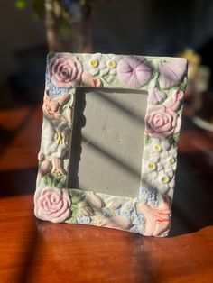 a small photo frame sitting on top of a wooden table next to a vase with flowers