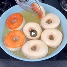 a blue bowl filled with doughnuts on top of a stove