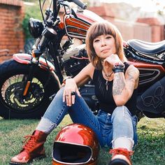 a woman sitting on the ground next to a motorcycle