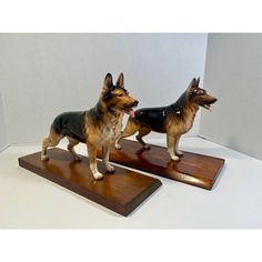 two german shepherd figurines on wooden bases