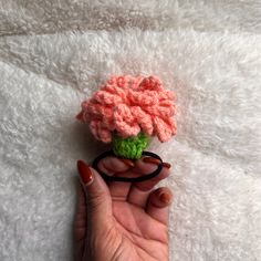 a crocheted flower being held by someone's hand on a white blanket