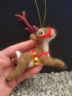 a hand holding a small christmas ornament in the shape of a reindeer's head