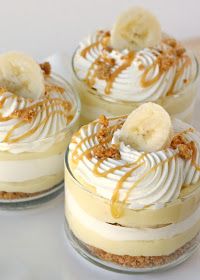 three desserts with banana slices and whip cream on top are sitting on a table