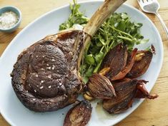 a white plate topped with meat and veggies on top of a wooden table