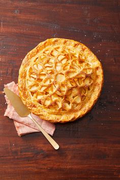 an apple pie on a wooden table with a serving utensil next to it