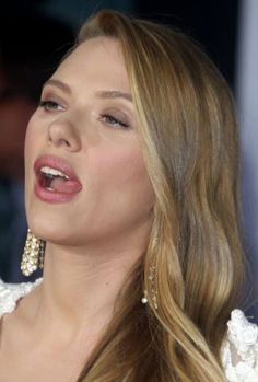 a close up of a woman with long hair and earrings on her head, looking off to the side