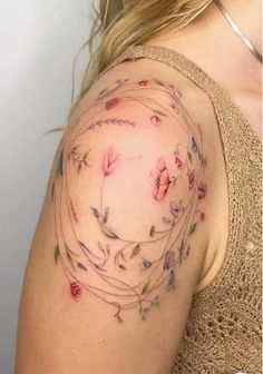 a woman's shoulder with flowers and vines on the back of her left arm