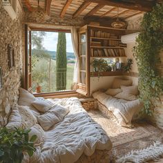 a bed sitting under a window next to a book shelf in a room filled with books