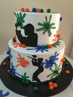 a three tiered cake decorated with handprints and colorful candies on top