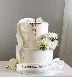 a white wedding cake with flowers and a cross on top