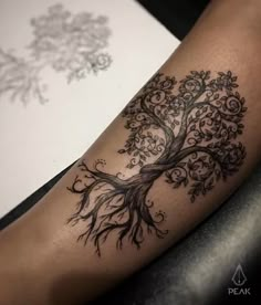 a black and white tree tattoo on the arm