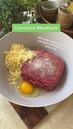 a white plate topped with meat and an egg next to grated parmesan cheese